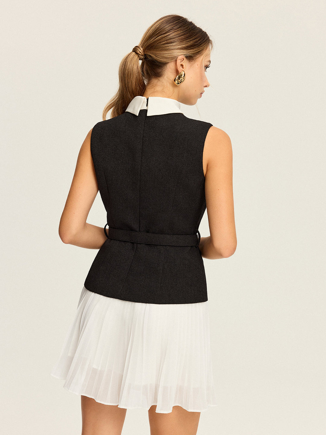 kolsuz, kemerli yelek ve pileli etek takımı